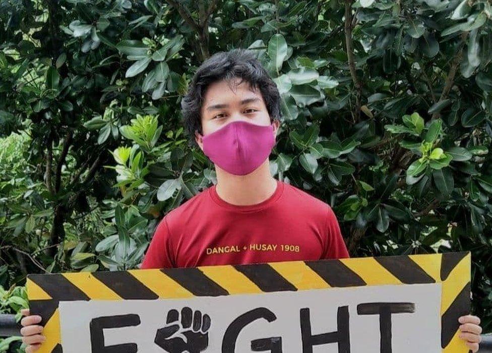 Jon Bonifacio holds a sign at a climate protest