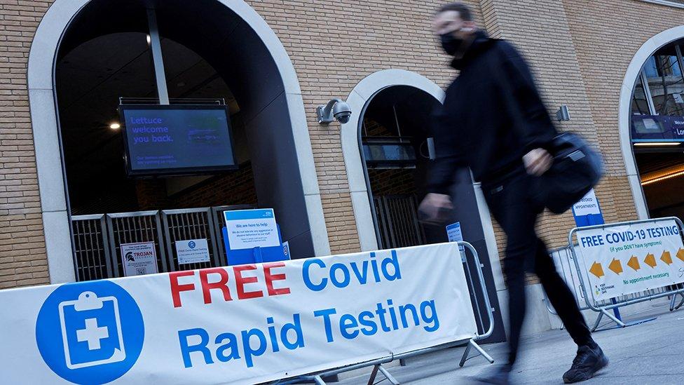 A pedestrian wearing a face covering walks past a sign directing people to a rapid lateral flow Covid-19 testing centre at London Bridge train station in central London on April 5, 2021.