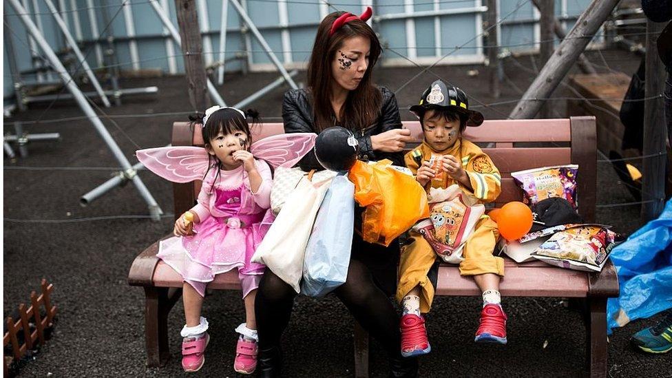 A woman giving snacks to children in costumes after a Halloween parade in Tokyo, Japan. 29 October 2016.