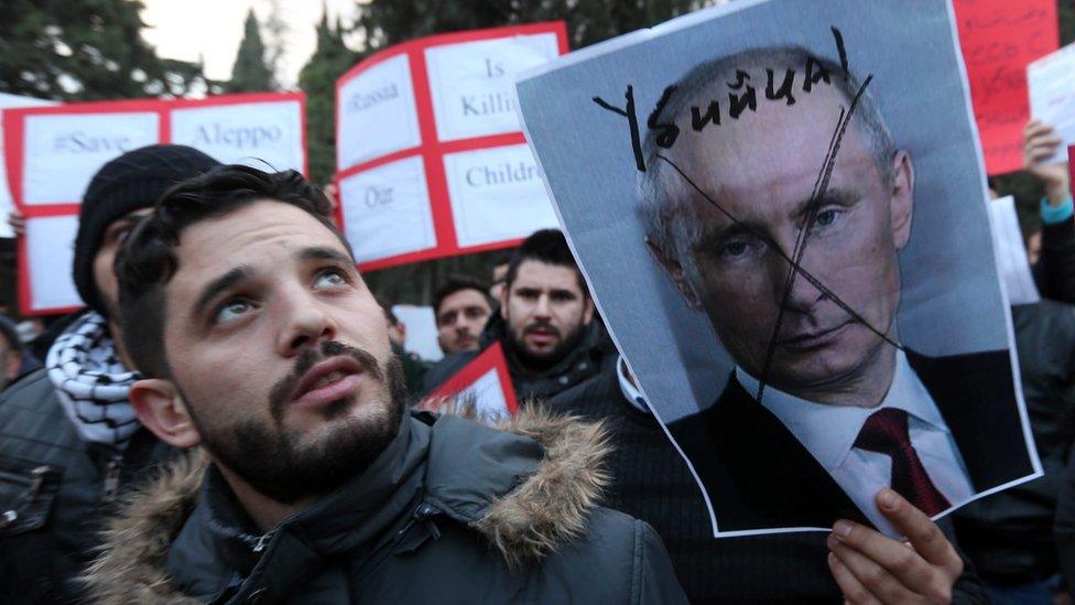 Jordanians and Syrian people living in Jordan hold a defaced photo of Russian President Vladimir Putin during a protest in front of Russian embassy in Amman, Jordan