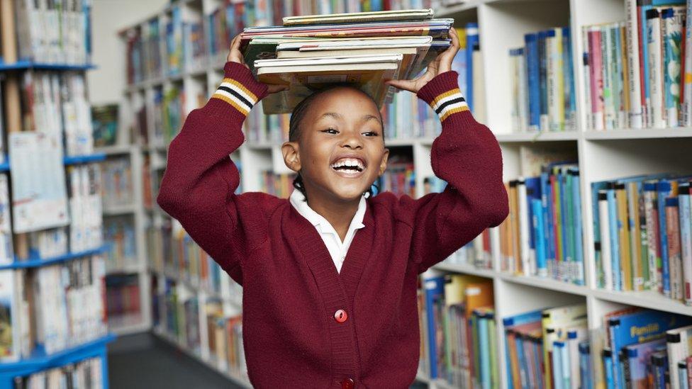 child-in-library-holding-books-on-head