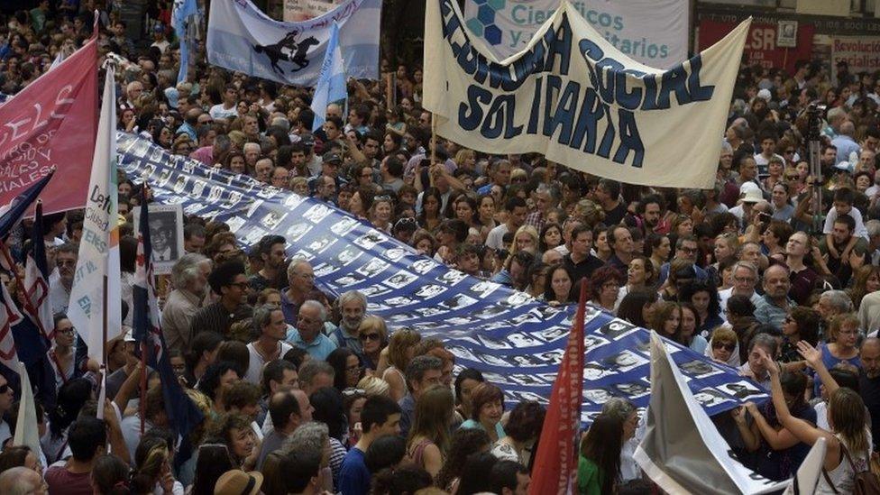 Members of the Mothers and Grandmothers of the Plaza de Mayo group carry a banner with pictures of victims of the military government