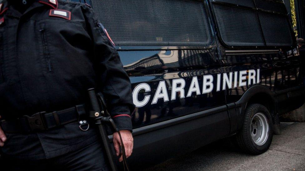 A member of the Italian carabinieri stands next to a marked car (file photo)