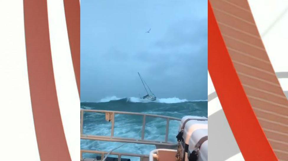 Yacht being towed by lifeboat in rough seas