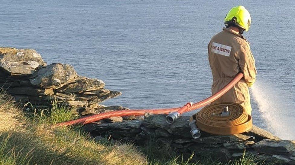 Fire fighter at the top of the hill tackling the fire below