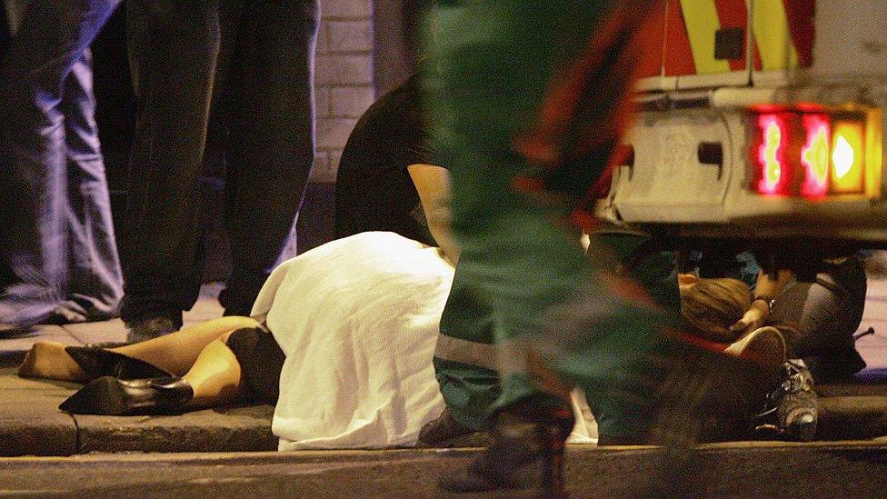 A clubber lies on the ground besides an ambulance