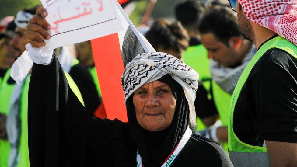 An Iraqi protester holds a sign reading "Brother don't kill me"