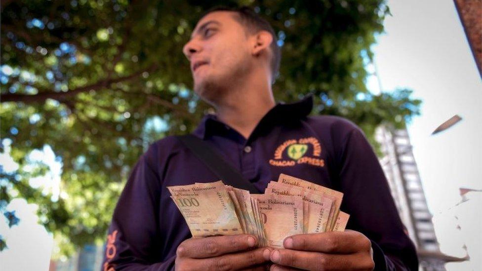 A man counts 100-Bolivar-bills in a street in Caracas on December 13, 2016. Venezuelan President Nicolas Maduro ordered on December 12 the border with Colombia sealed for 72 hours, accusing US-backed "mafias" of conspiring to destabilize his country's economy by hoarding bank notes.