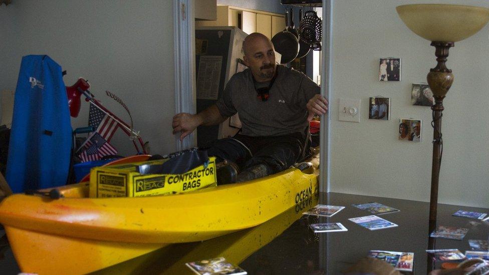 arry Koser Jr. (L) and his son Matthew look for important papers and heirlooms inside Larry Koser Sr."s house after it was flooded by heavy rains from Hurricane Harvey August 29, 2017 in the Bear Creek neighborhood of west Houston, Texas.