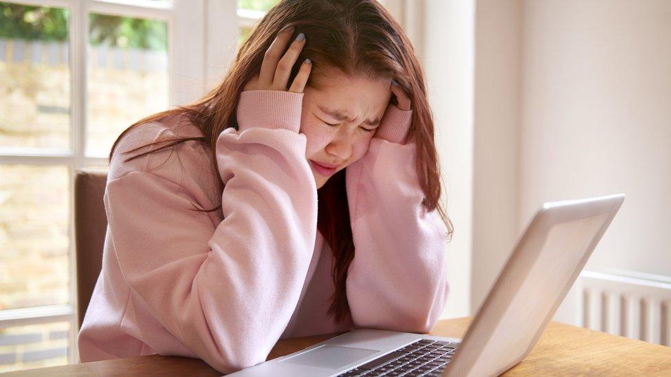 A girl in distress sitting in front of her laptop