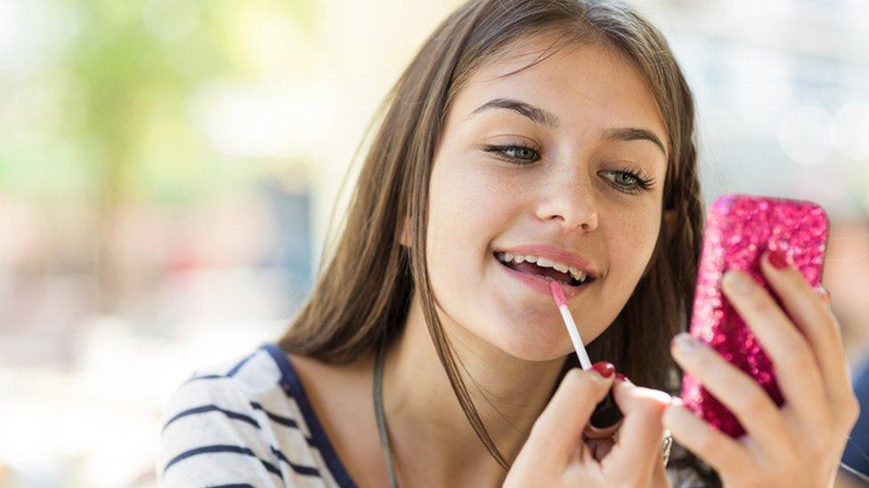 Teenage girl applies make-up (posed by model)