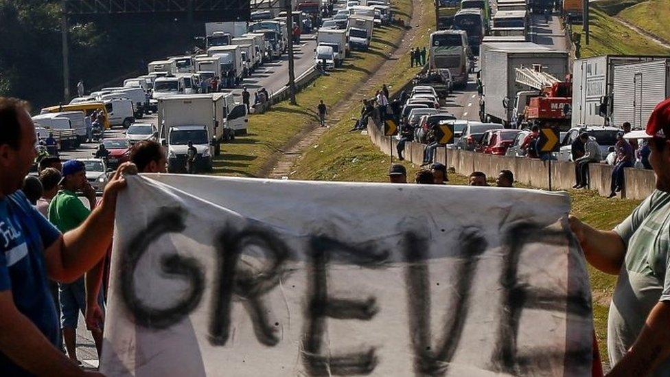 Brazilian truck drivers hold a banner reading "strike" as they block the Regis Bittencourt road, 30 kilometres from Sao Paulo.