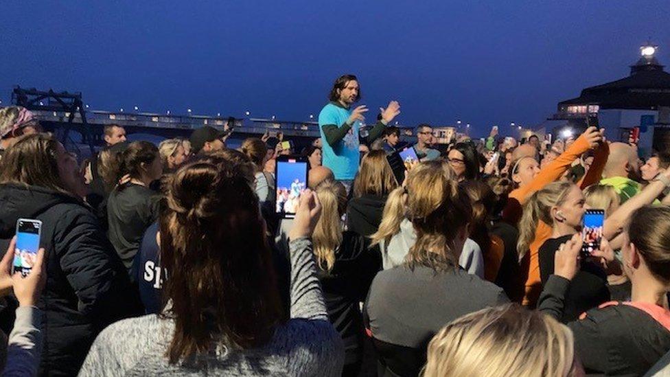 Joe Wicks talking to a crowd of people who are filming him on their phones