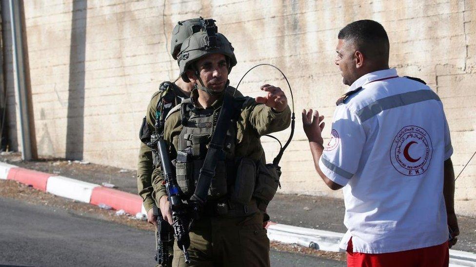 Israeli soldier and Palestinian medic gesture to one another at scene of shooting (25/07/23)