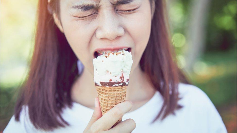 girl grimaces while eating an ice cream