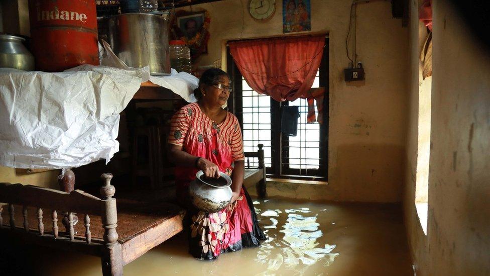 A woman stands in her flooded home