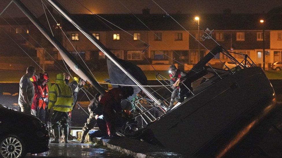 Members of the Coast Guard inspect the damage to a boat after it broke free from its berth and crashed into the harbour during Storm Betty in Dungarvan, County Waterford.