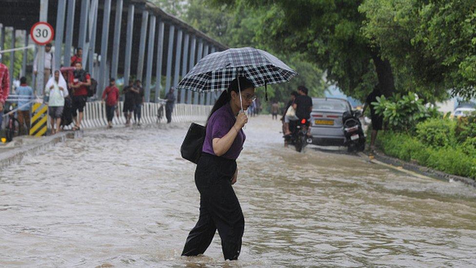 Commuters cross a waterlogged stretch following heavy monsoon rains at sector-38 near Tau Devi Lal Stadium, on July 9, 2023