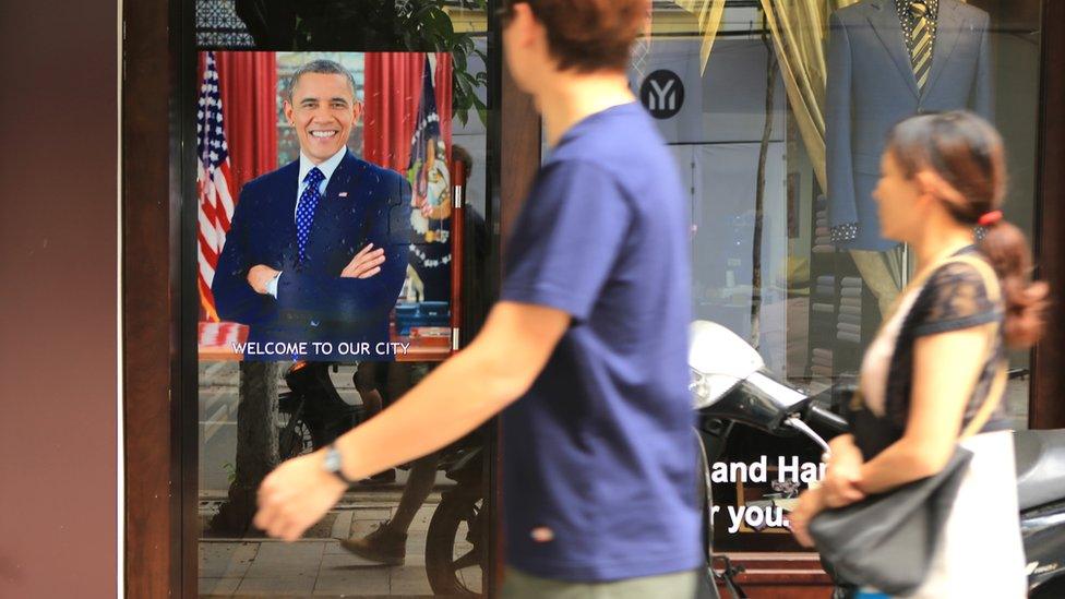 A Vietnamese couple pass a poster of U.S President Barack Obama with footnote read "Welcome to our city"