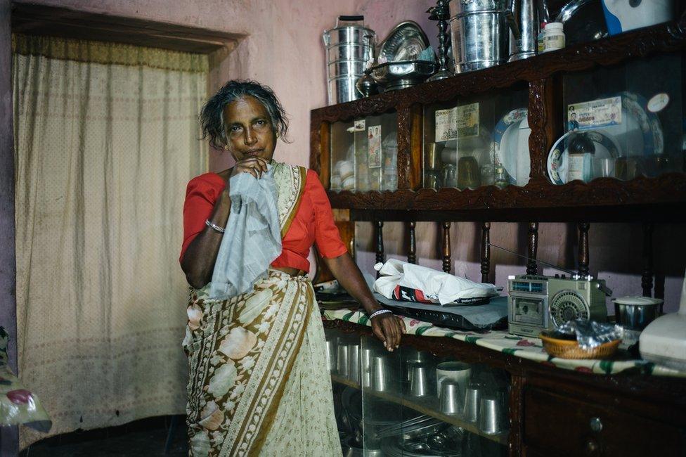 A tea plucker poses inside her house