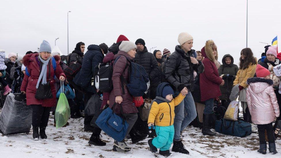 Refugees fleeing conflict make their way to the Krakovets border crossing with Poland