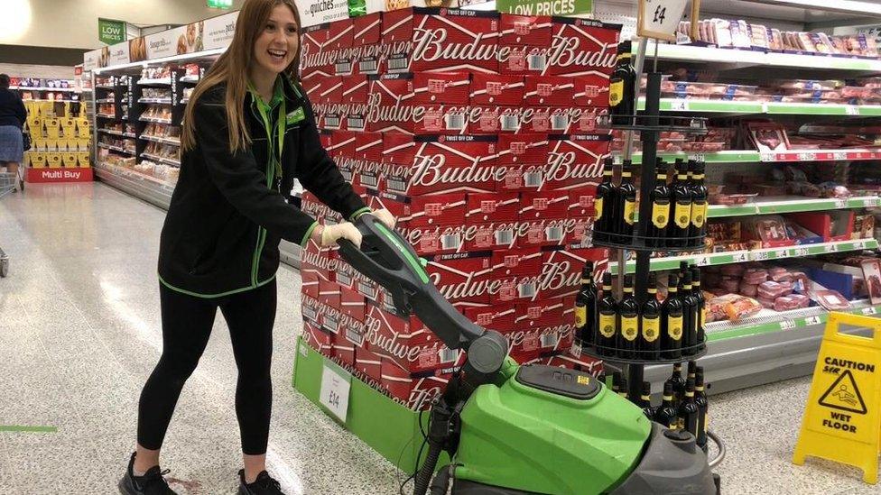 Megan is in a supermarket using a floor cleaning machine