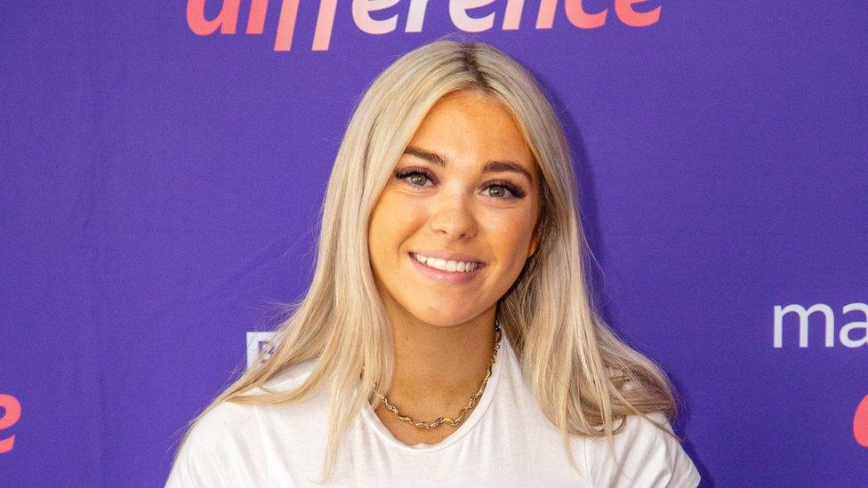 A young woman with blonde hair smiles at the camera