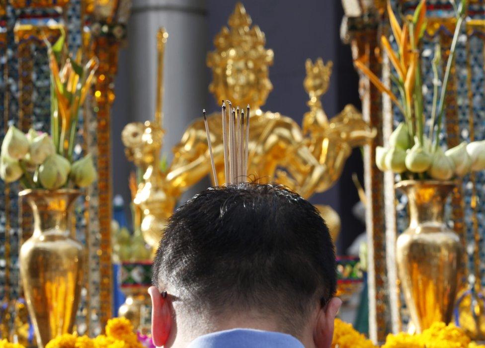 A man burns joss stick at a statue of Lord Brahma, the Hindu God of Creation, at the Erawan Shrine in Bangkok, Thailand, 9 September 2015.