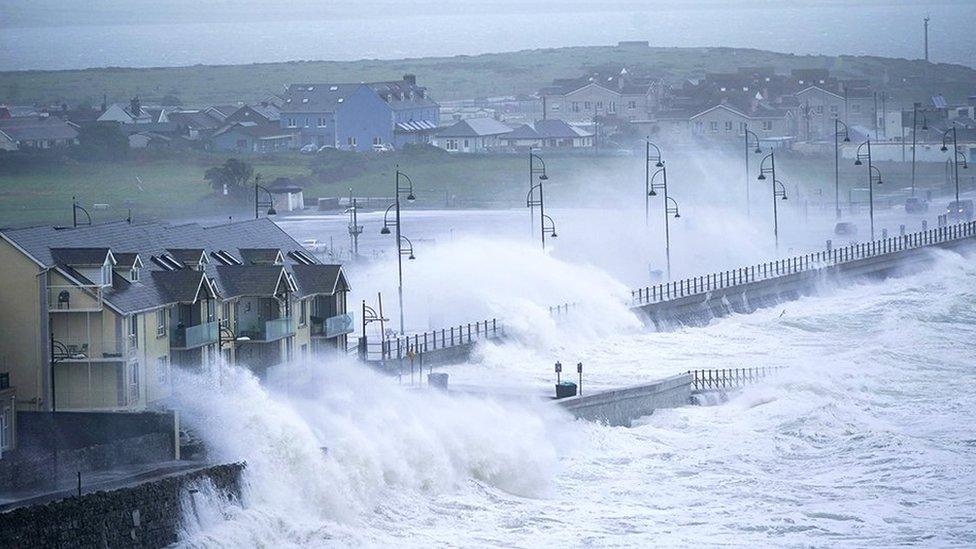 Waves lash the Irish coast, spraying buildings and a road