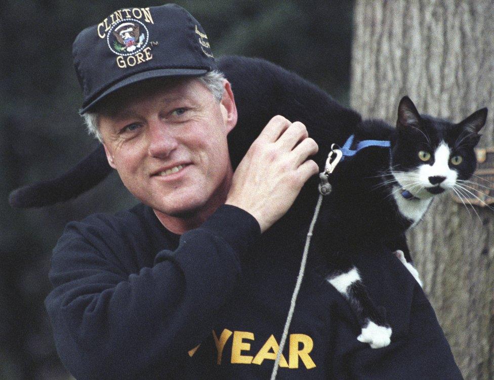 President Clinton stands with his pet cat socks on his shoulders