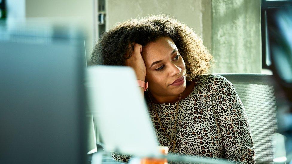 Woman looking fed up at her desk at work