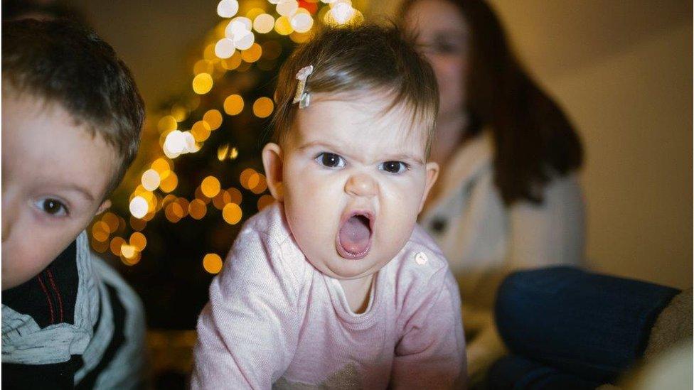 Baby in front of Christmas lights