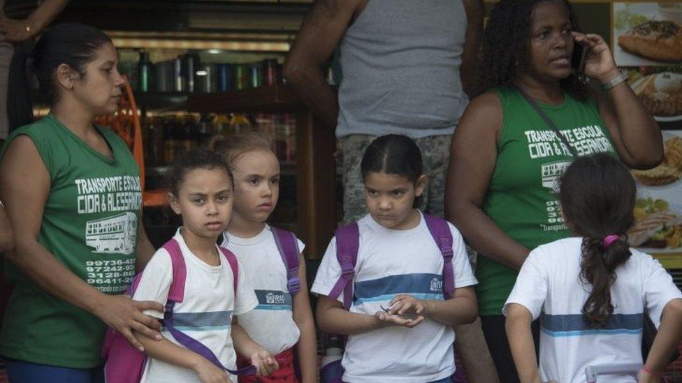 Workers of a school transport company wait with schoolchildren at the entrance of the Rocinha favela during a joint operation by the Police and Brazilian Armed Forces to fight heavily armed drug traffickers there, in Rio de Janeiro, Brazil, on September 22, 2017.