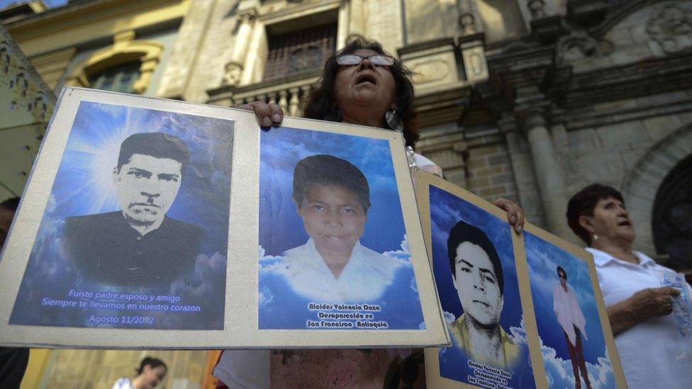 A protester holds portraits of disappeared relatives in Medellin