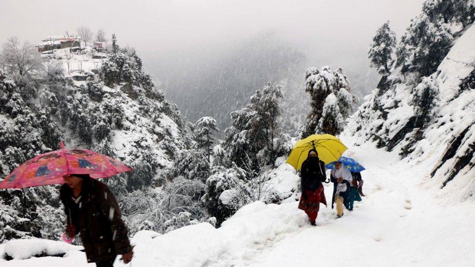 People walking along a snowy mountain path