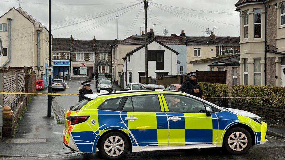 A police car and officers in front of a cordon