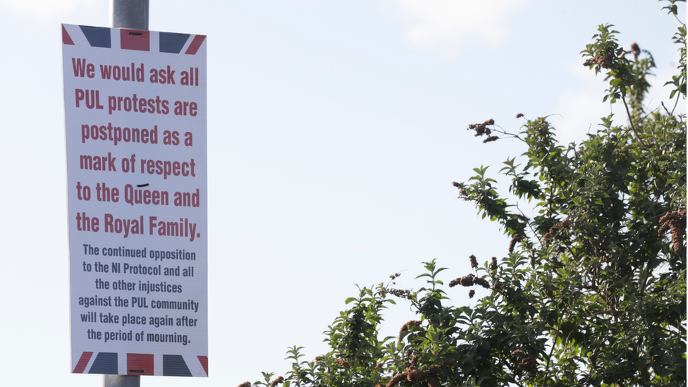 A sign showing a message to loyalist protesters to delay their protests as a sign of respect