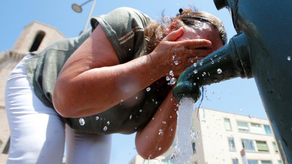 A woman cools off in a water fountain in Marseille as a heatwave hits France in June