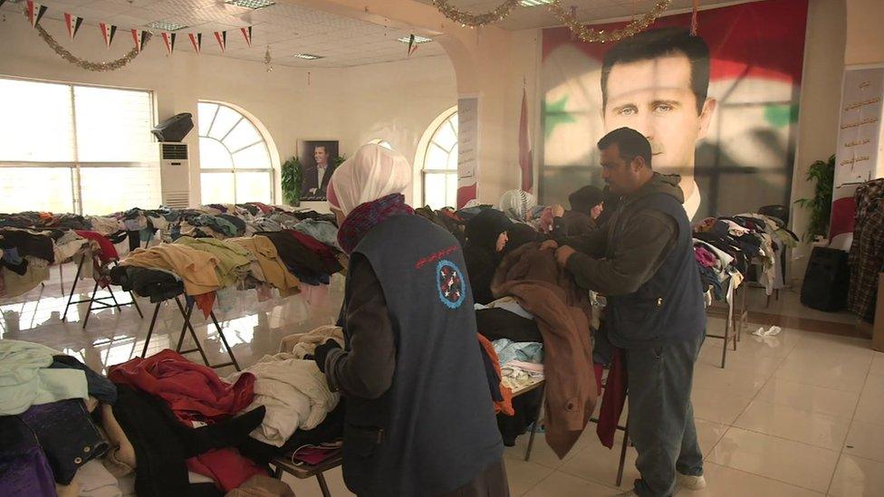 People sort through donated clothes at a shelter for internally displaced people in Damascus