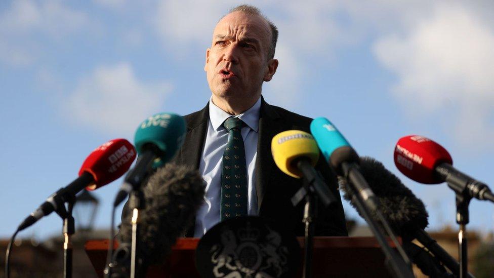 Chris Heaton-Harris stands behind a range of microphones at a press conference