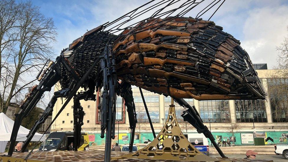 A giant bee sculpture made out of knifes and guns