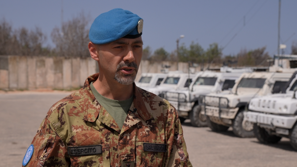 Colonel Alberto Salvador standing in front of a row of white UN trucks