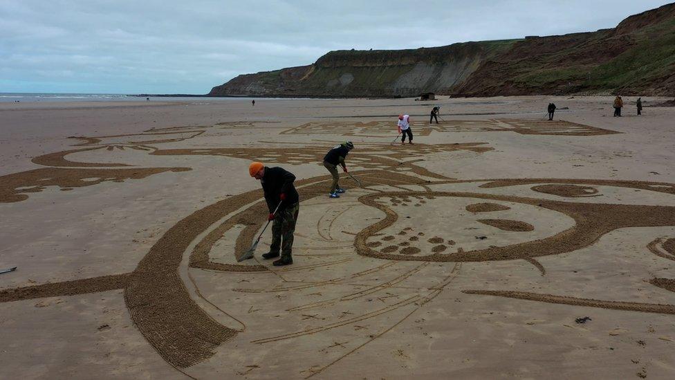 People creating a sand drawing