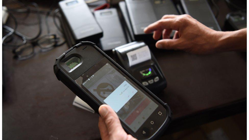 An Independent Election Commission worker tests a biometric device at a warehouse in Kabul.