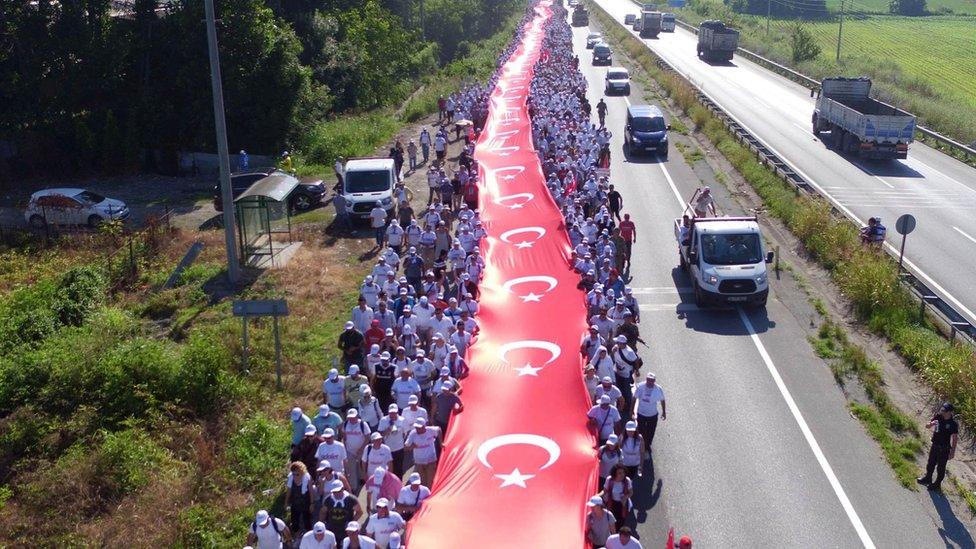 Thousands of supporters hold a long Turkish national flag on the march to Istanbul