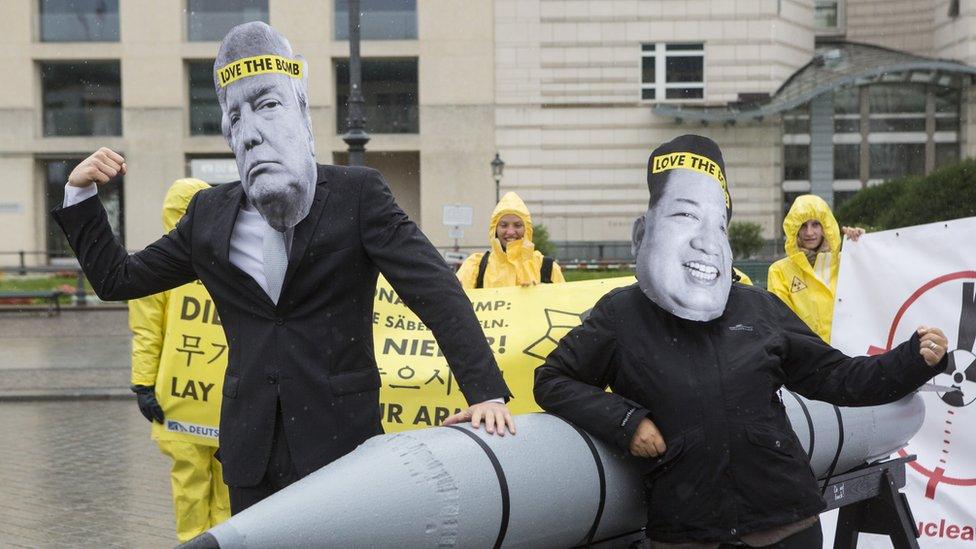 International campaign to abolish Nuclear Weapons (ICAN) activists wearing masks to look like US President Donald Trump and North Korean Kim Jong-Un pose next to a Styrofoam effigy of a nuclear bomb while protesting in front of the American Embassy on September 13, 2017 in Berlin, Germany