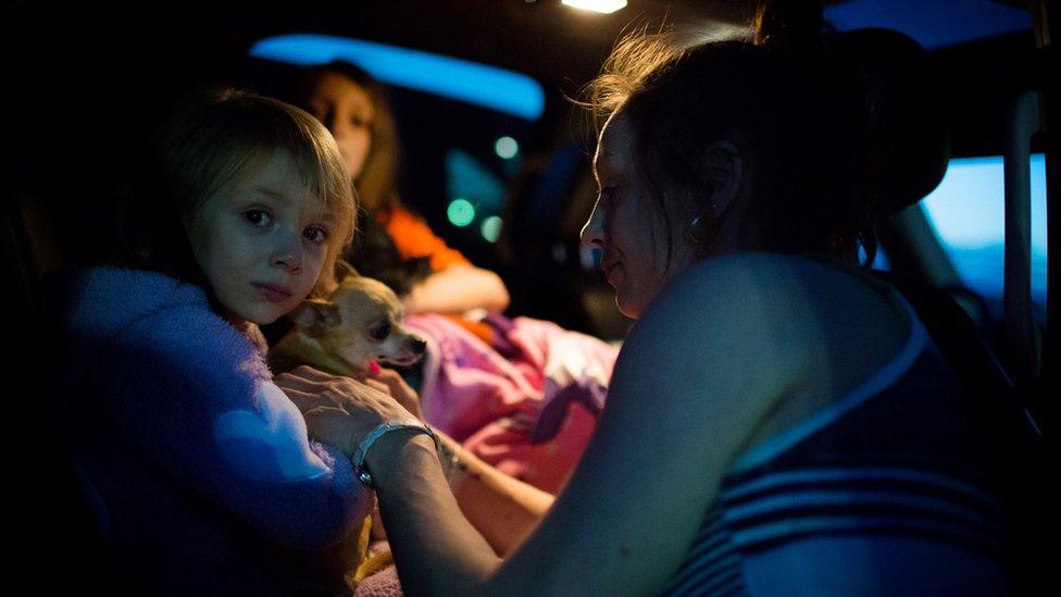 Fort McMurray resident Crystal Maltais buckles in her daughter, Mckennah Stapley, as they prepare to leave Conklin, Alberta