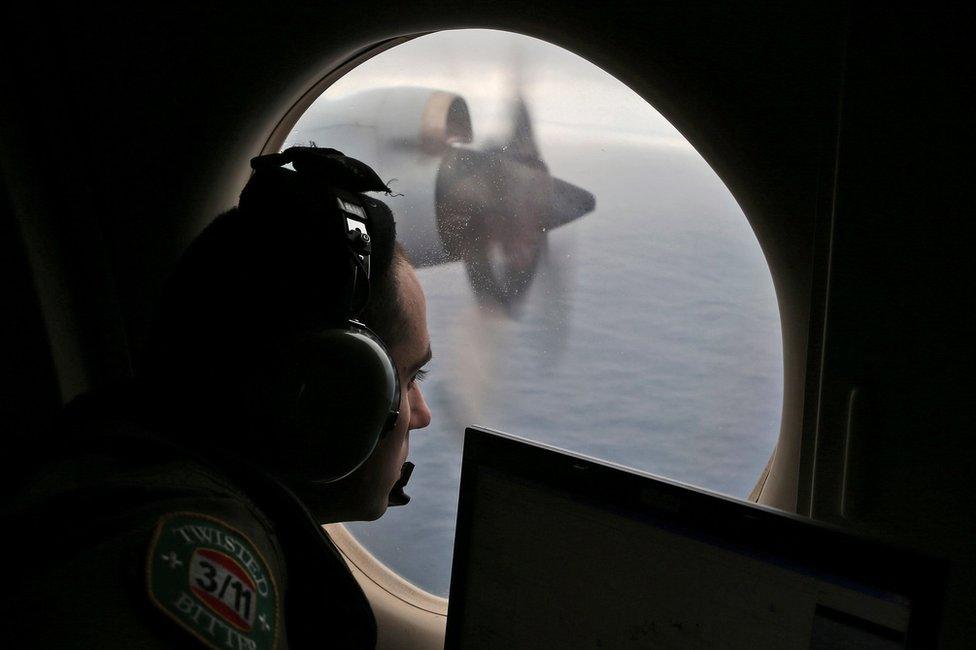 In this March 22, 2014 file photo, flight officer Rayan Gharazeddine scans the water in the southern Indian Ocean off Australia from a Royal Australian Air Force AP-3C Orion during a search for the missing Malaysia Airlines Flight MH370.