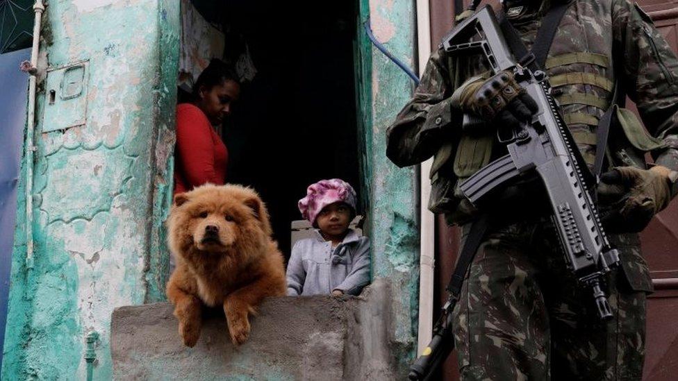 Armed Forces members patrol, as residents watch, during an operation against organized crime in Manguinhos slum complex in Rio de Janeiro, Brazil, August 21, 2017.