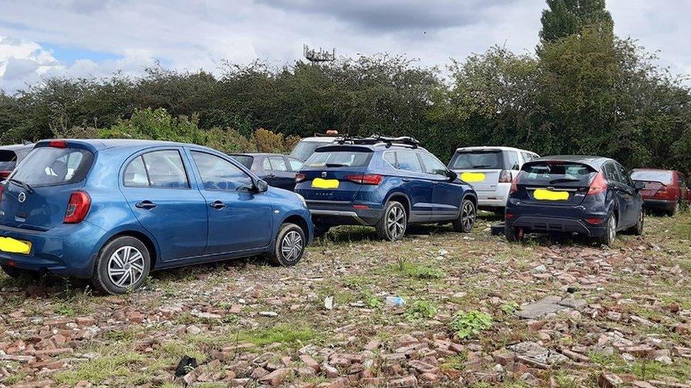 Cars parked on field littered with bricks